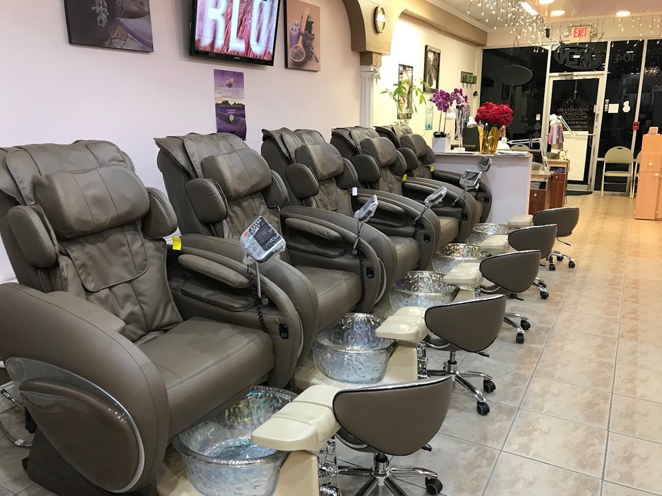 Manicured hands with glossy pink nails on a salon chair.